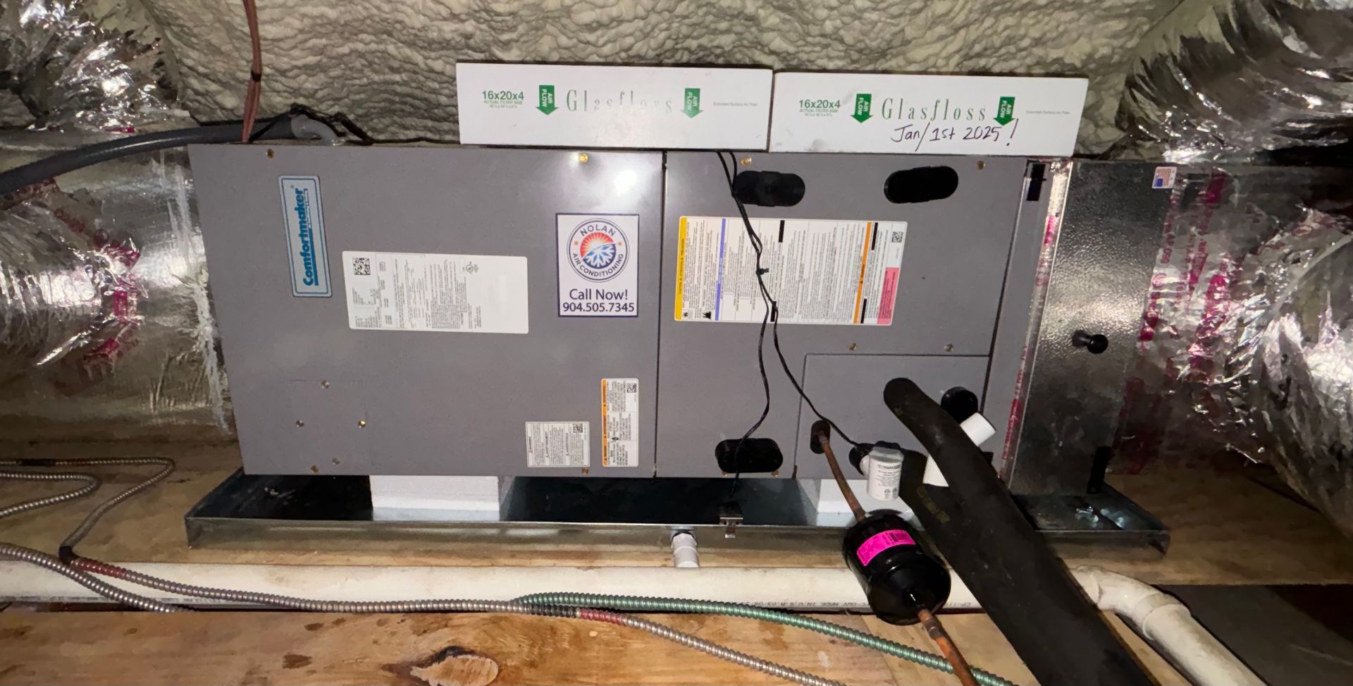 An air conditioner is sitting on top of a wooden floor in a room.