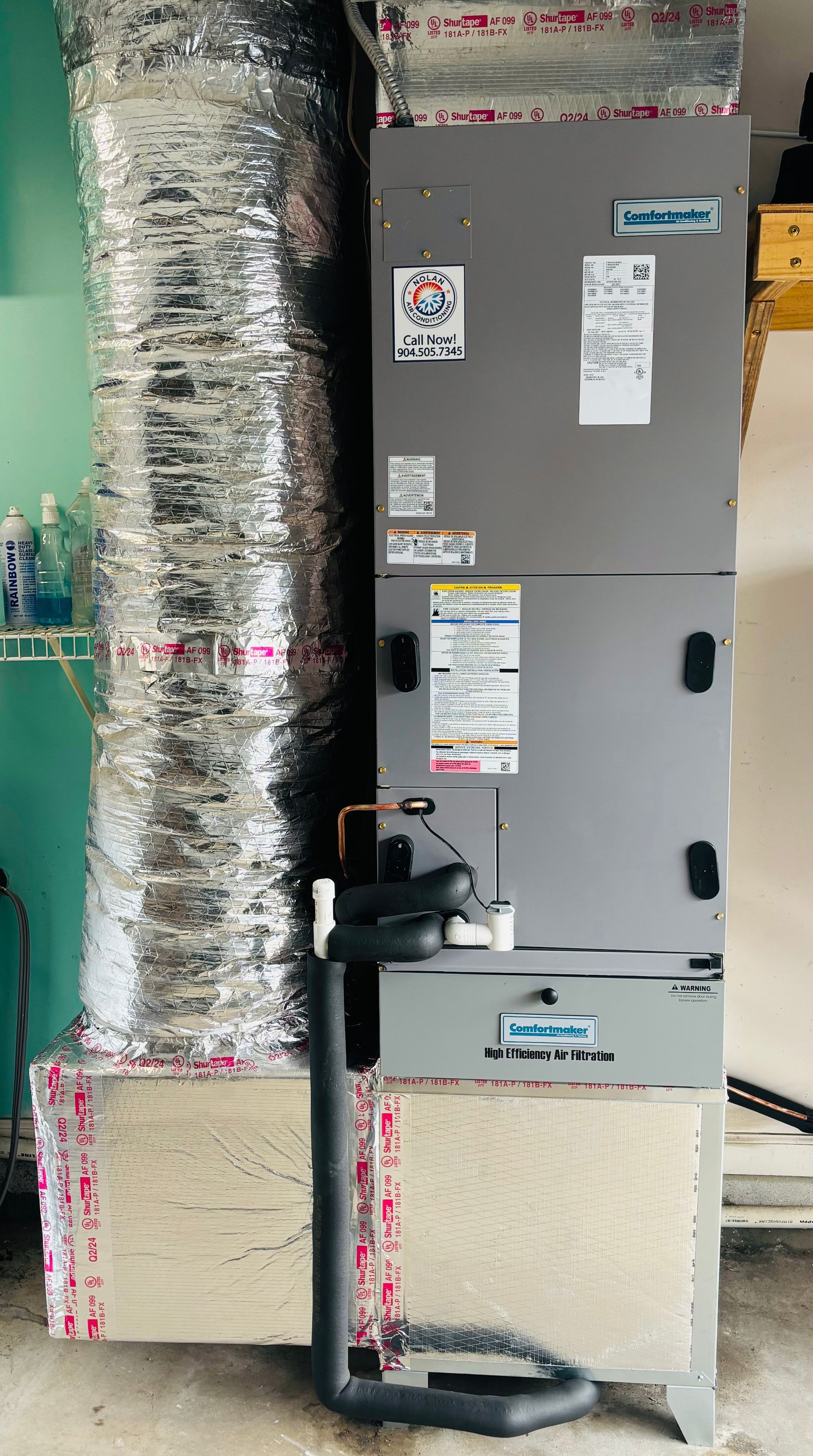 A gray air conditioner is sitting on top of a wooden table in a garage.