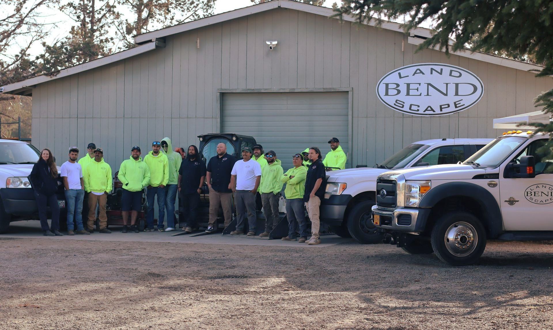 Landscapers, many wearing neon vests, stand in front of a building with 
