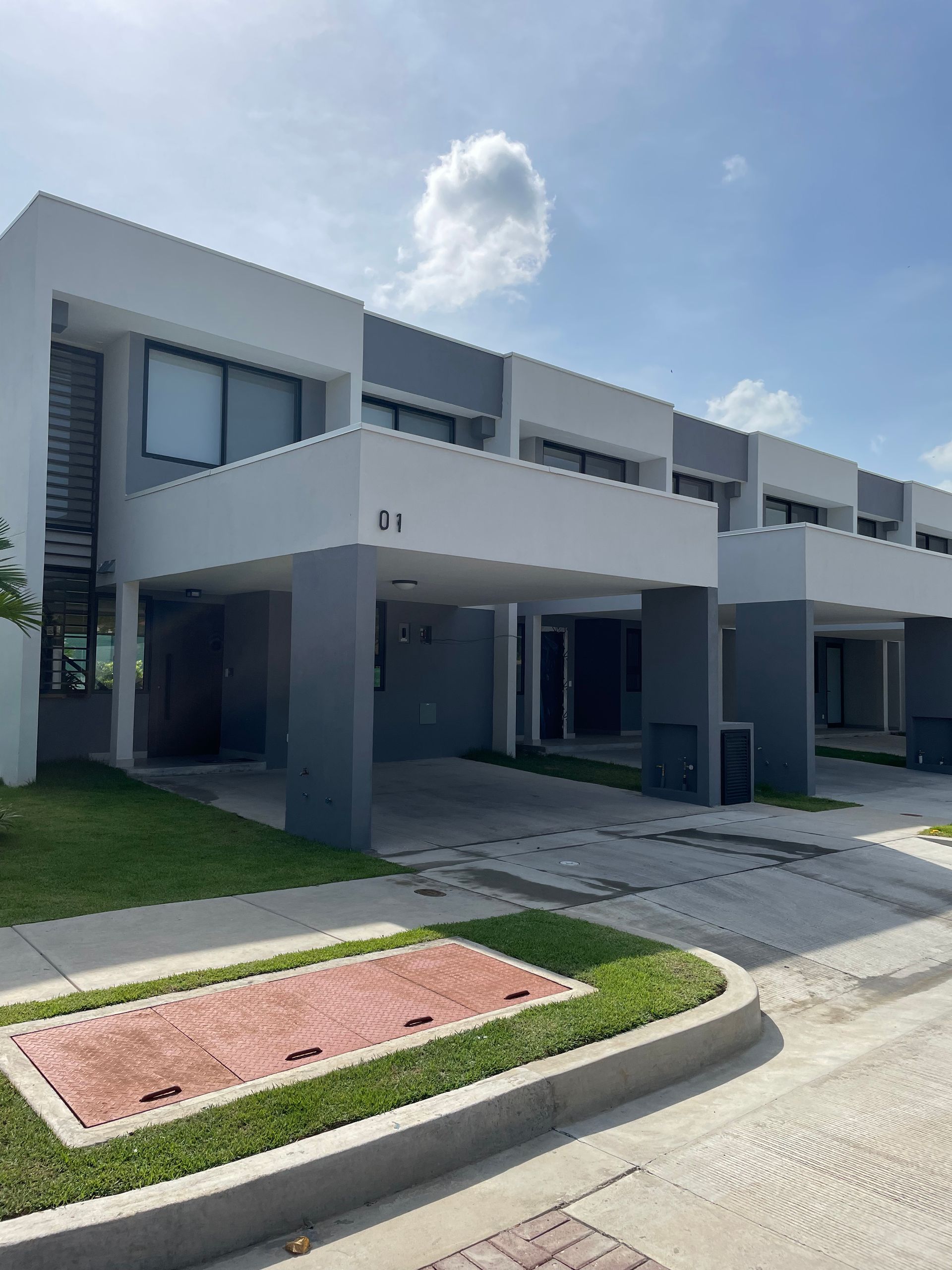 Un gran edificio blanco y gris con muchas ventanas y una entrada para coches.