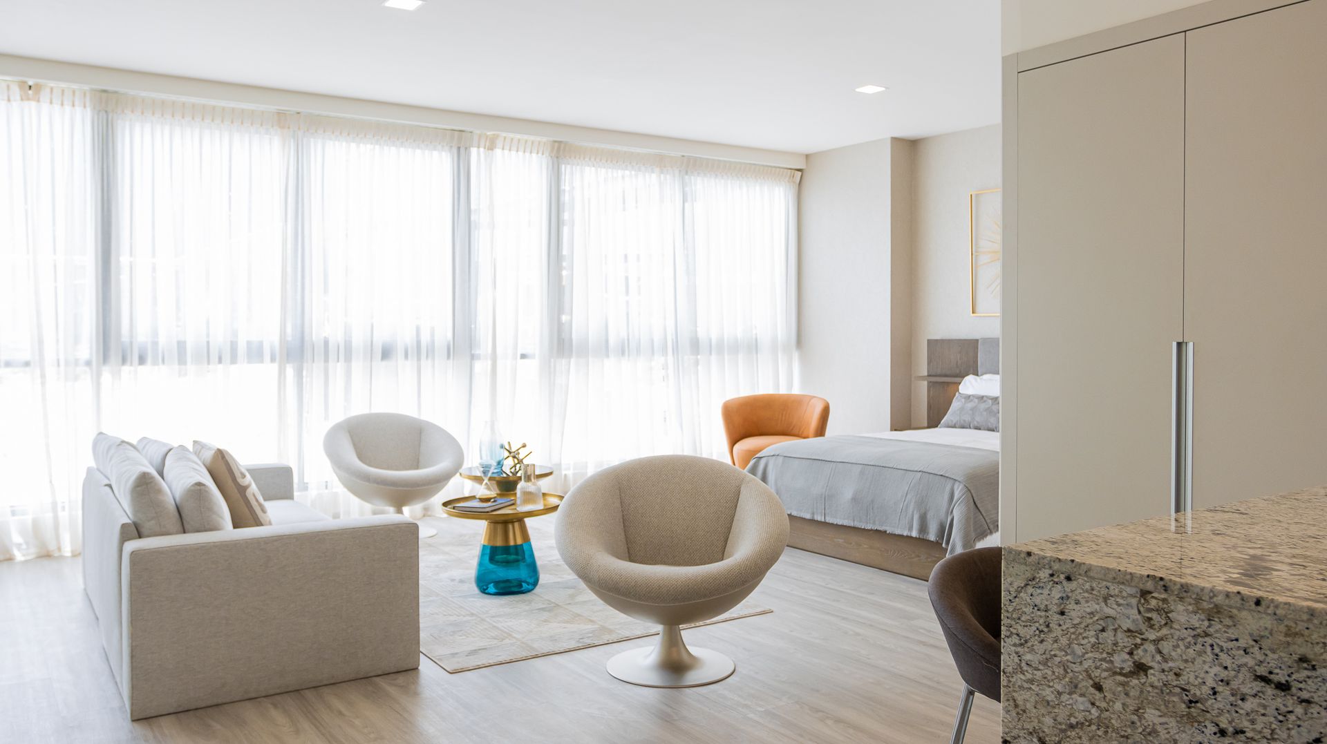 Una sala de estar con un sofá, sillas, una mesa y una cama.