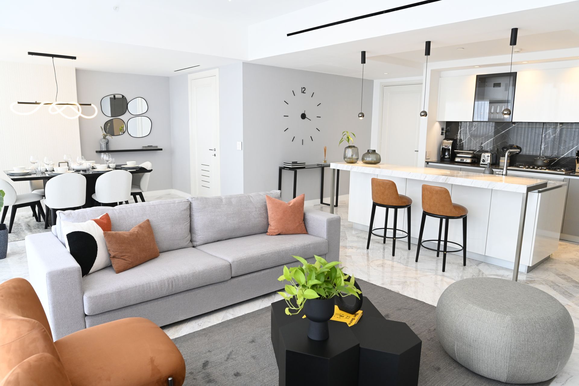 Una sala de estar con un sofá, una silla, una mesa de café y un reloj en la pared.