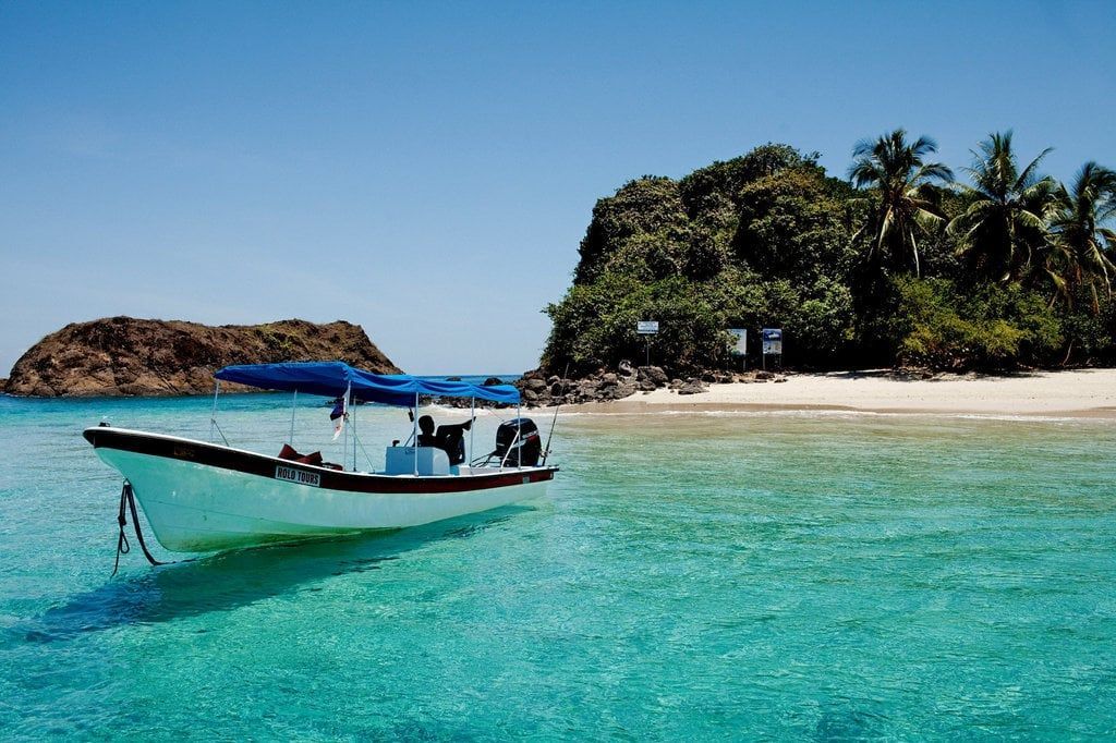 Un barco flota en el océano cerca de una pequeña isla.