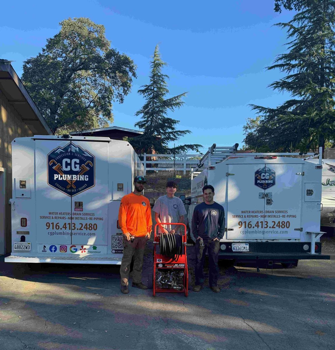 Three men are standing in front of two cg plumbing trucks