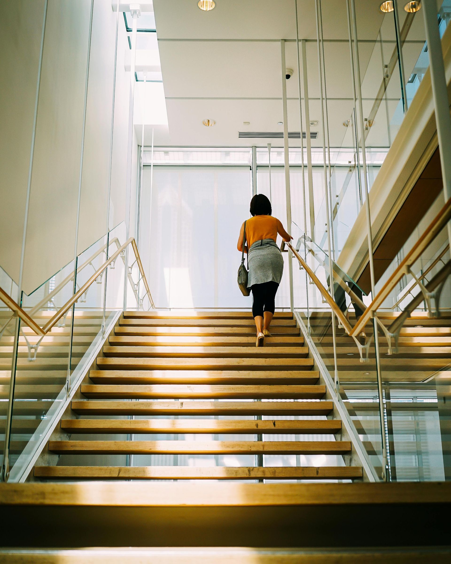 A woman is walking up a set of stairs in a building.