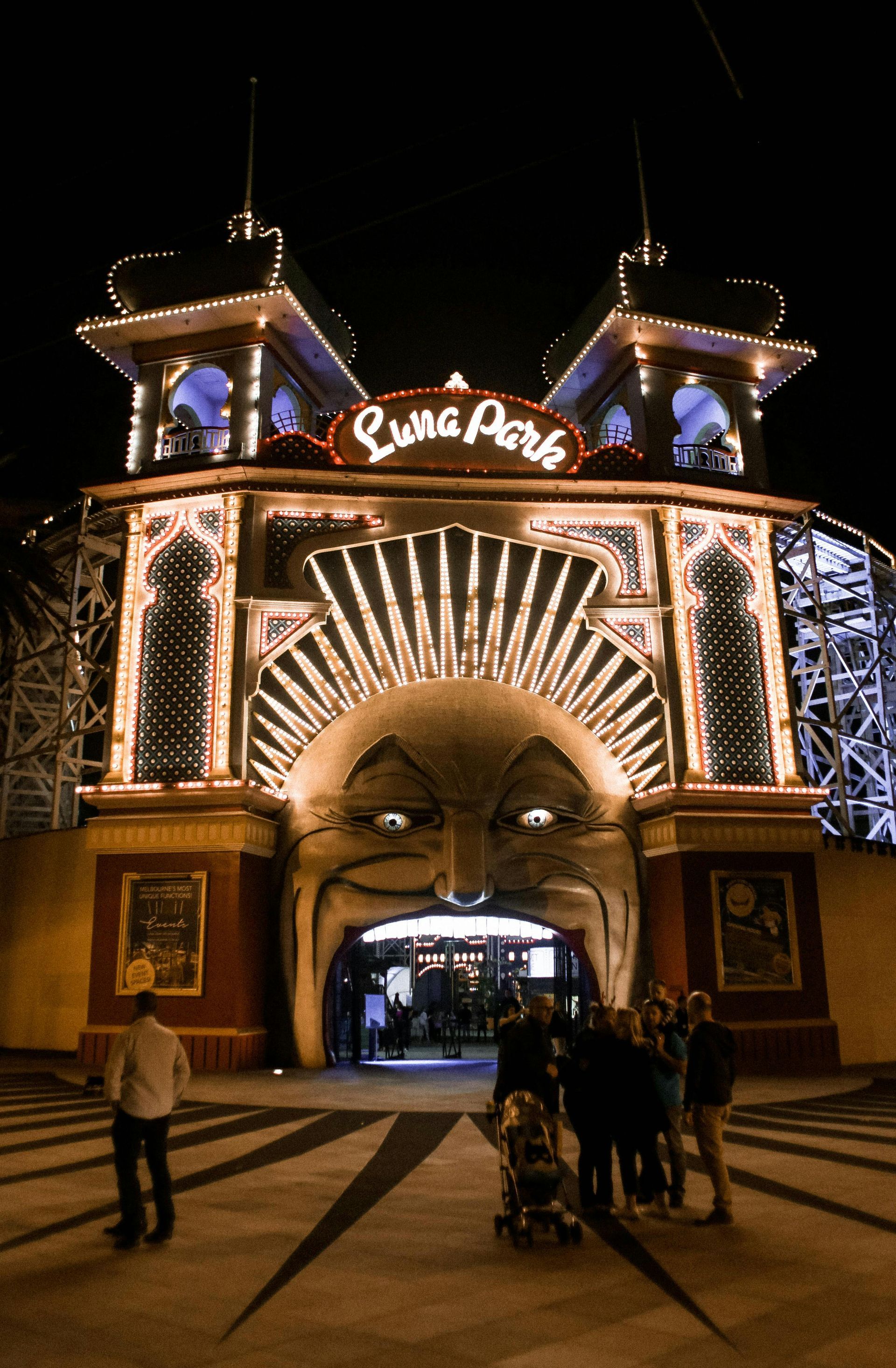 A group of people are standing in front of Luna Park in Melbourne.