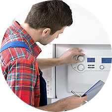A man in a plaid shirt is working on a boiler while holding a clipboard.