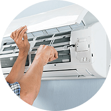 A man is fixing an air conditioner with a screwdriver.