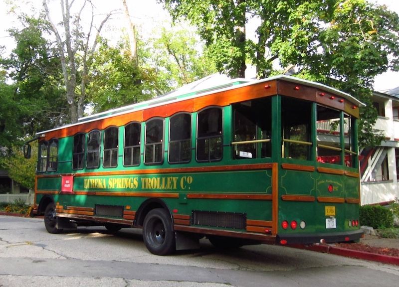 A green trolley is parked on the side of the road