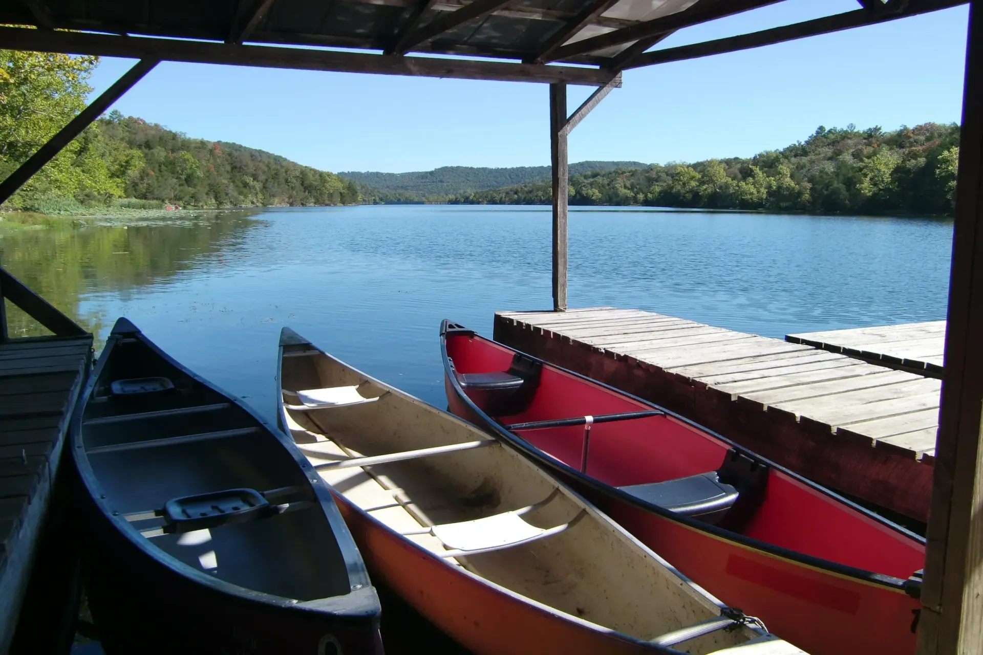 Two canoes are sitting on a dock near a lake