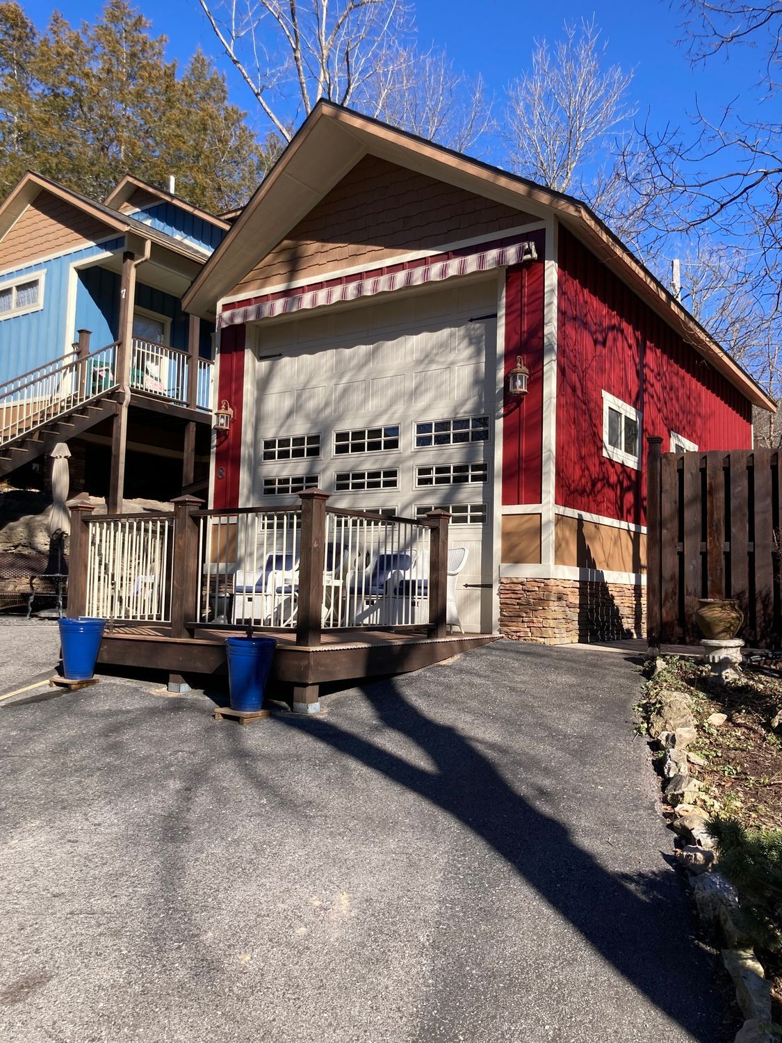 A red house with a white garage door and a wooden deck.