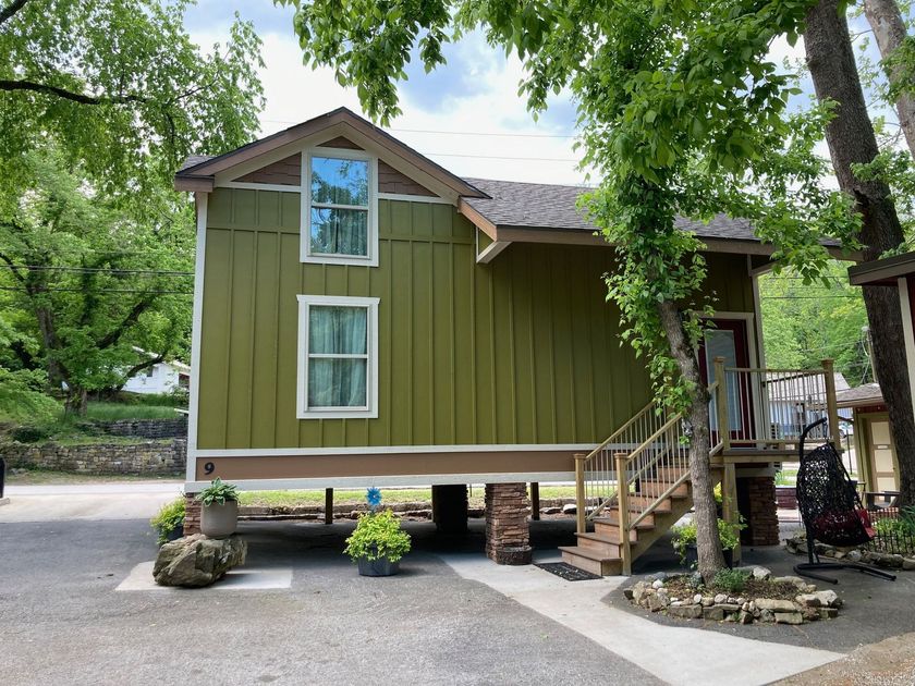 A small green house with stairs leading up to it is on stilts.