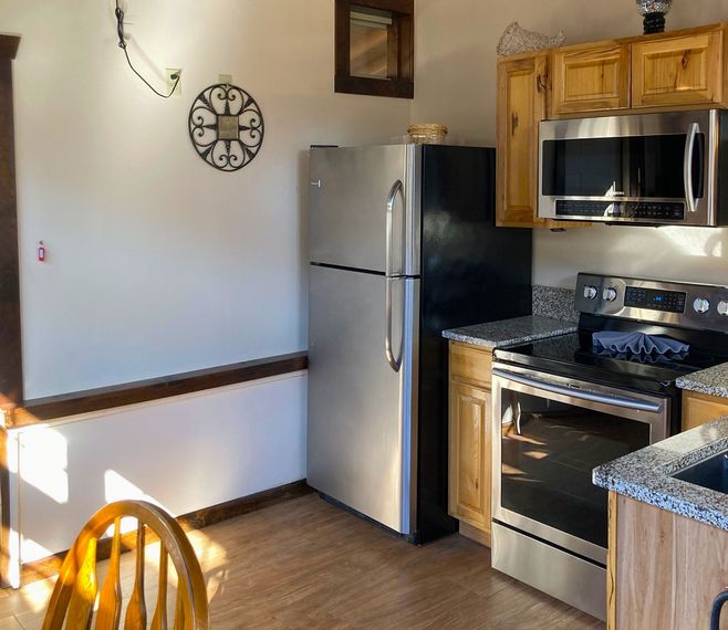 A kitchen with a clock on the wall above the refrigerator