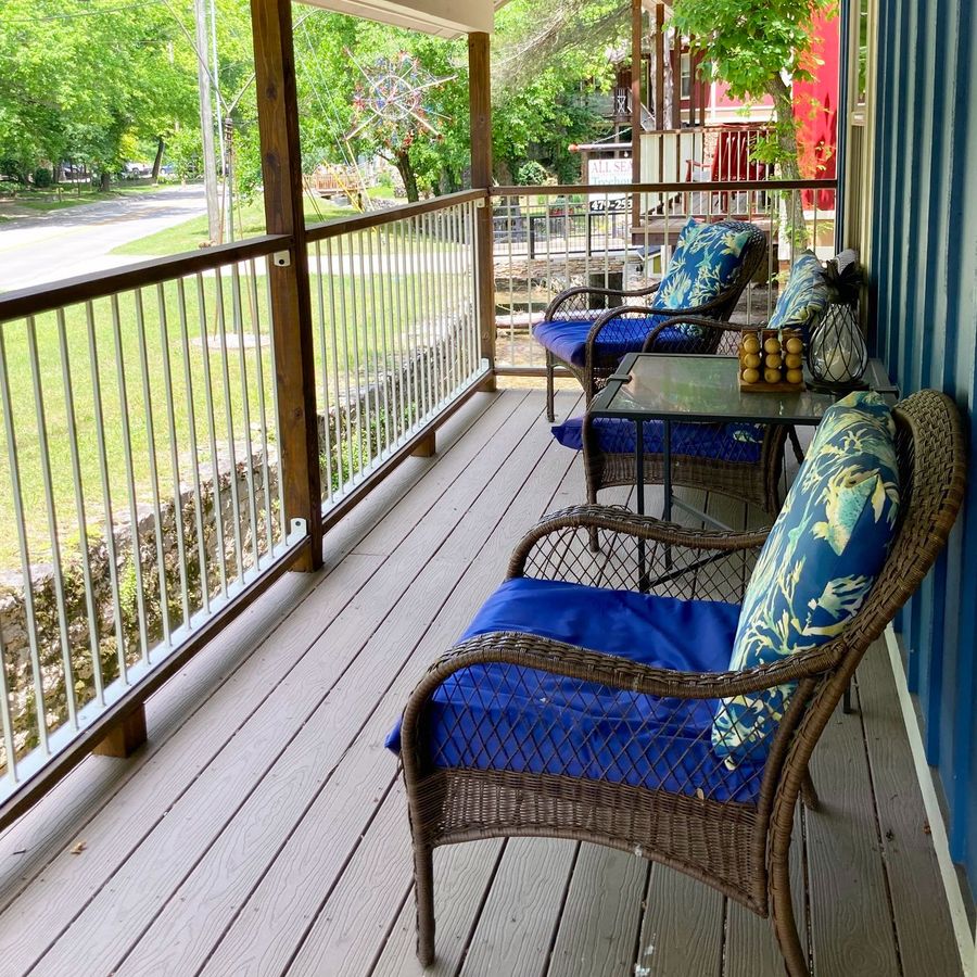 A porch with wicker furniture and blue cushions.