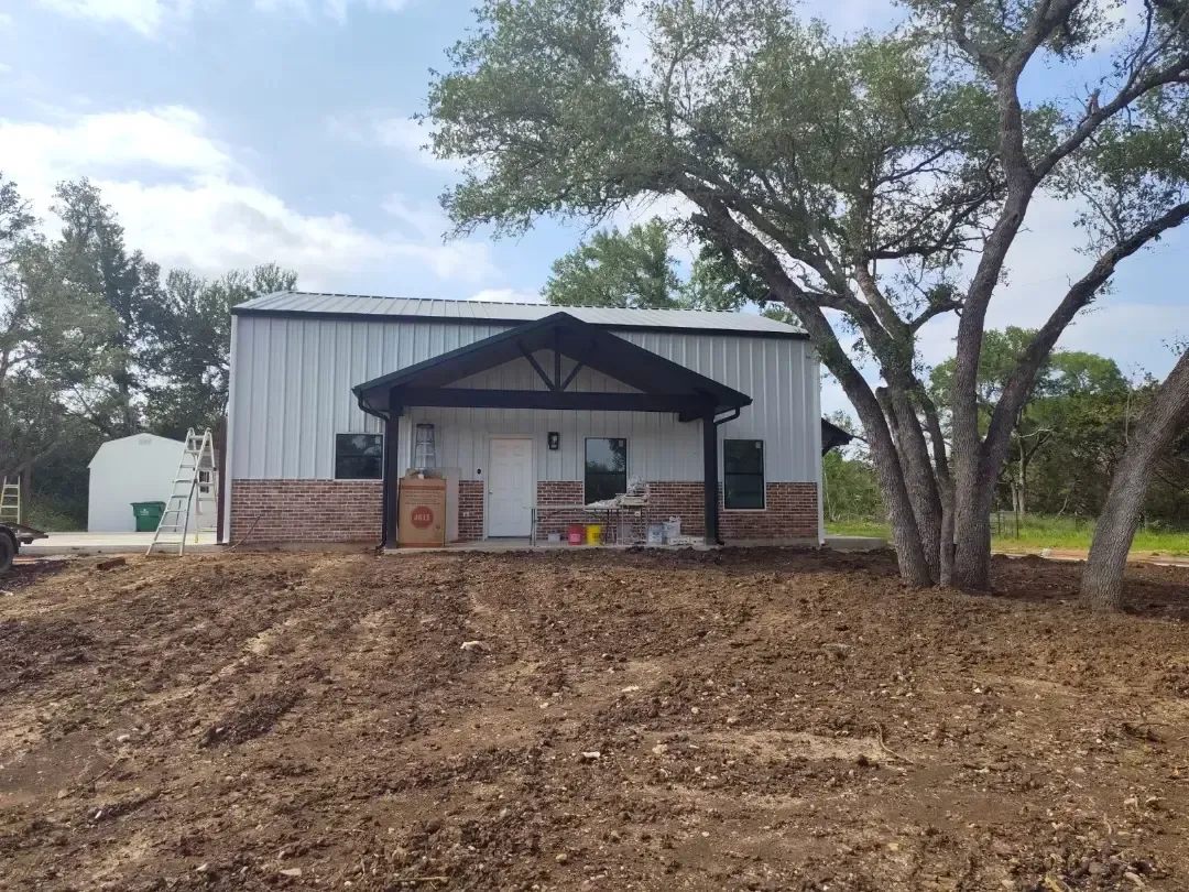 A white house is sitting in the middle of a dirt field.