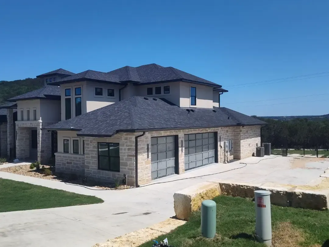 A large house with a gray roof is sitting on top of a hill.