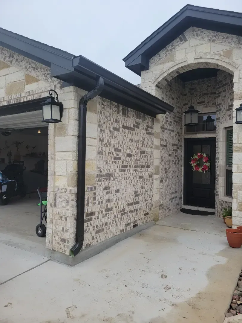 A brick house with a black gutter and a black door