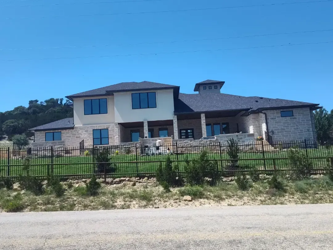 A large house with a fence around it is sitting on top of a hill.