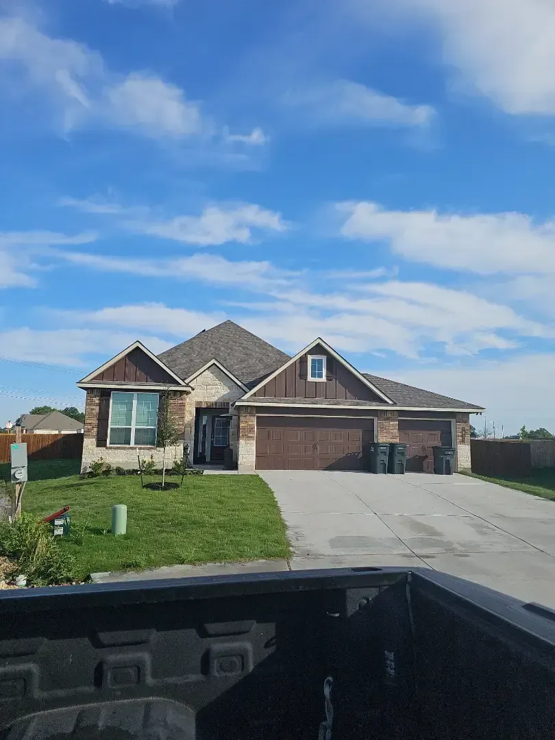 A truck is parked in front of a house on a sunny day