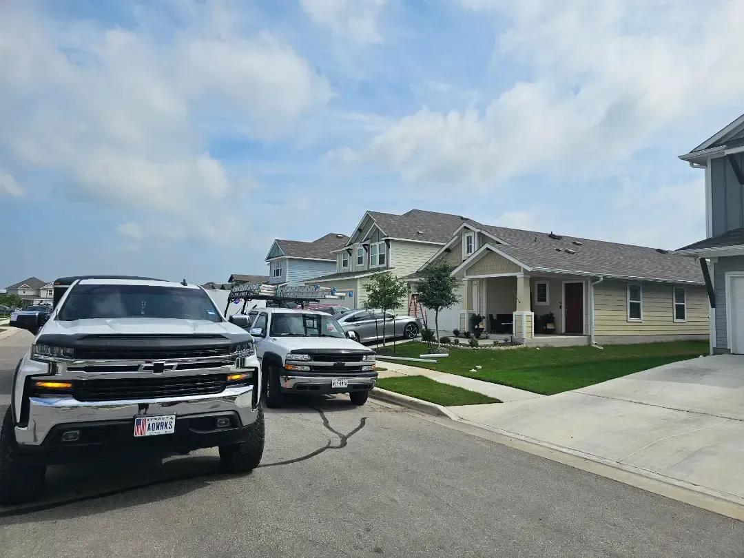 A couple of cars are parked on the side of the road in front of a house.