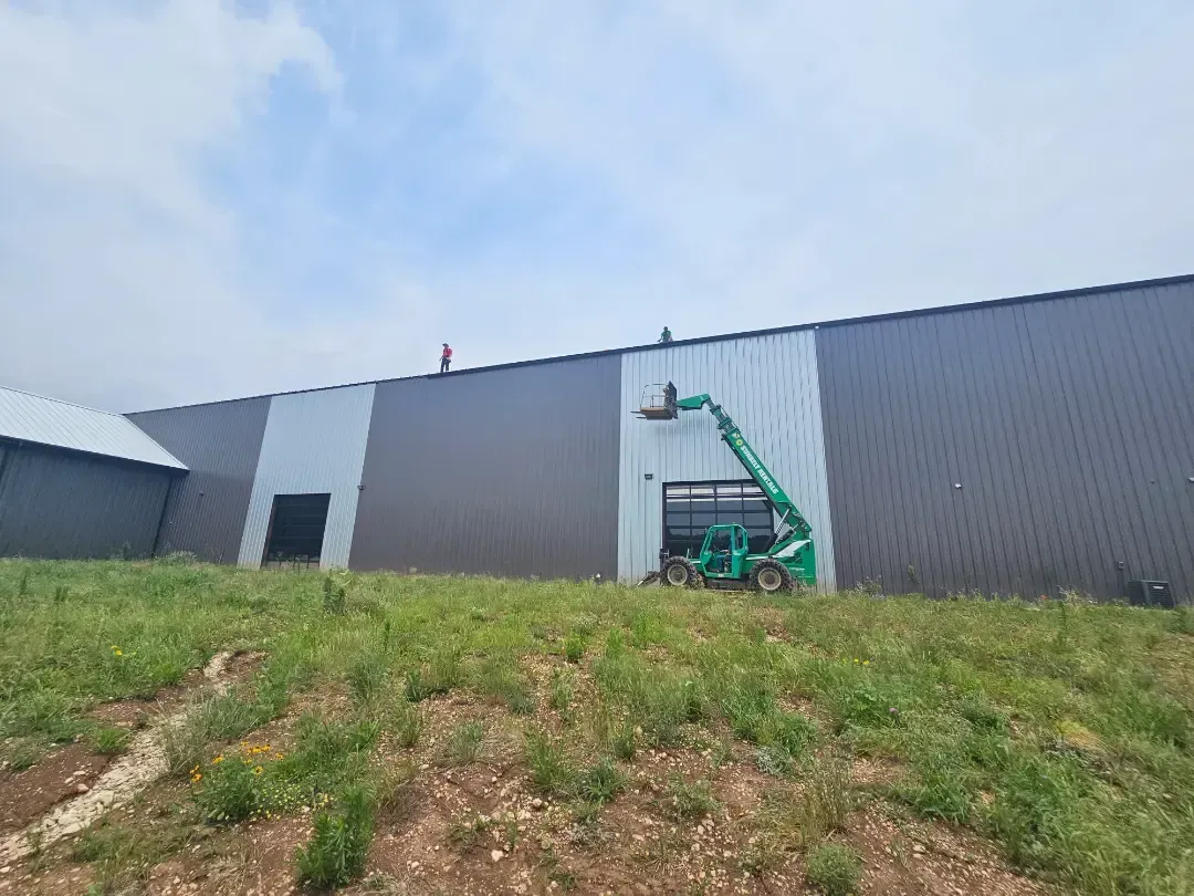 A large building with a crane on the side of it is being painted.