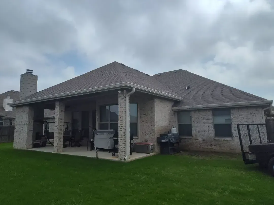 The back of a brick house with a covered patio and a lot of windows.