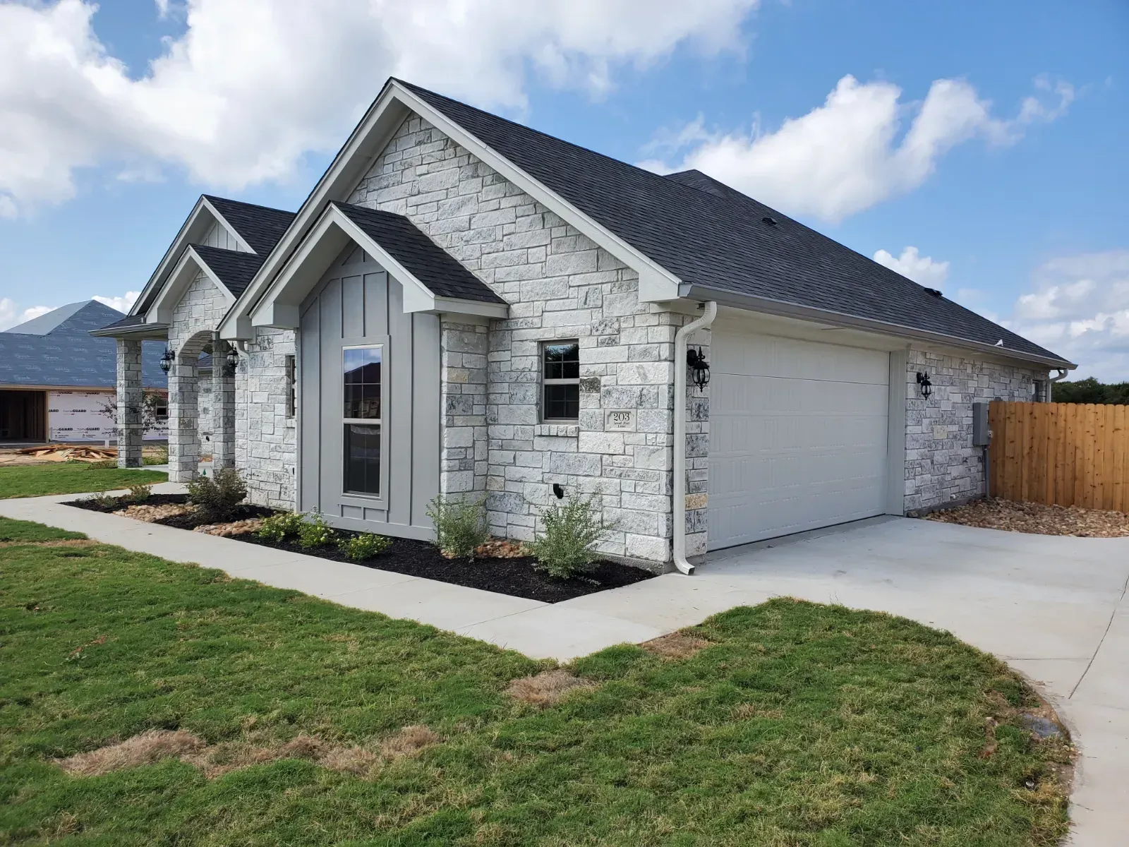 A white house with a garage and a fence in front of it.