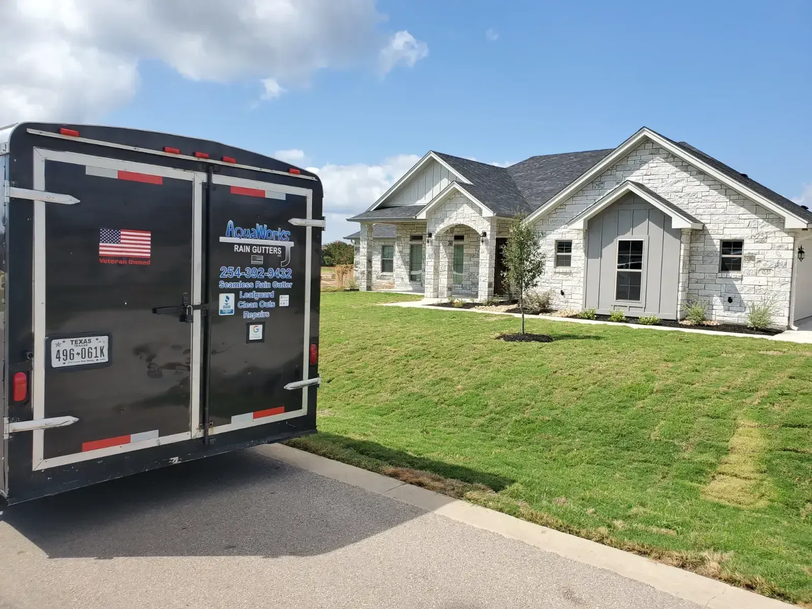 A black trailer is parked in front of a house.