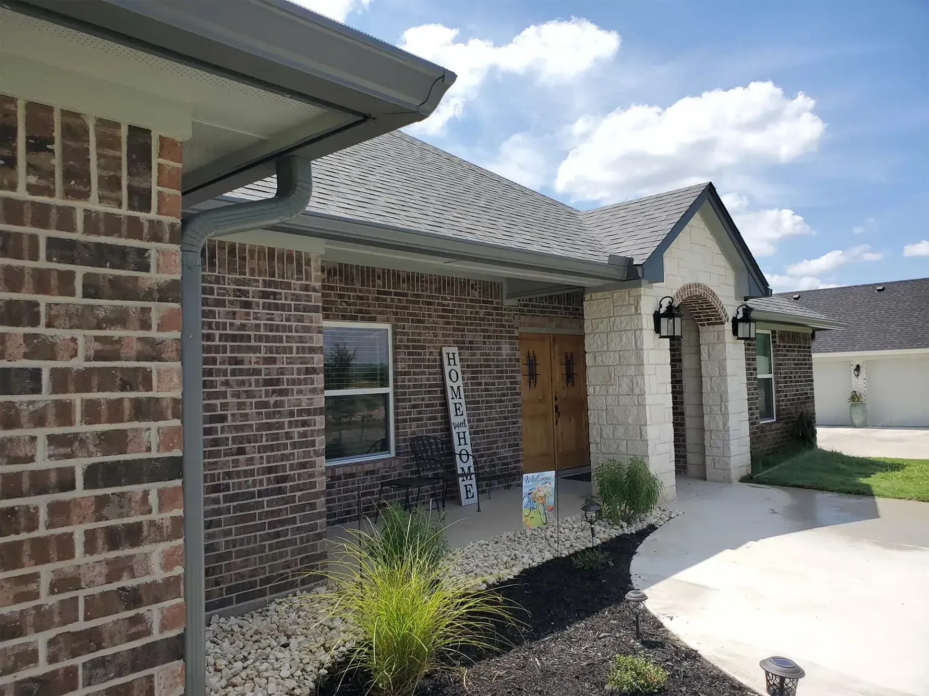 A brick house with a gutter and a ladder in front of it.