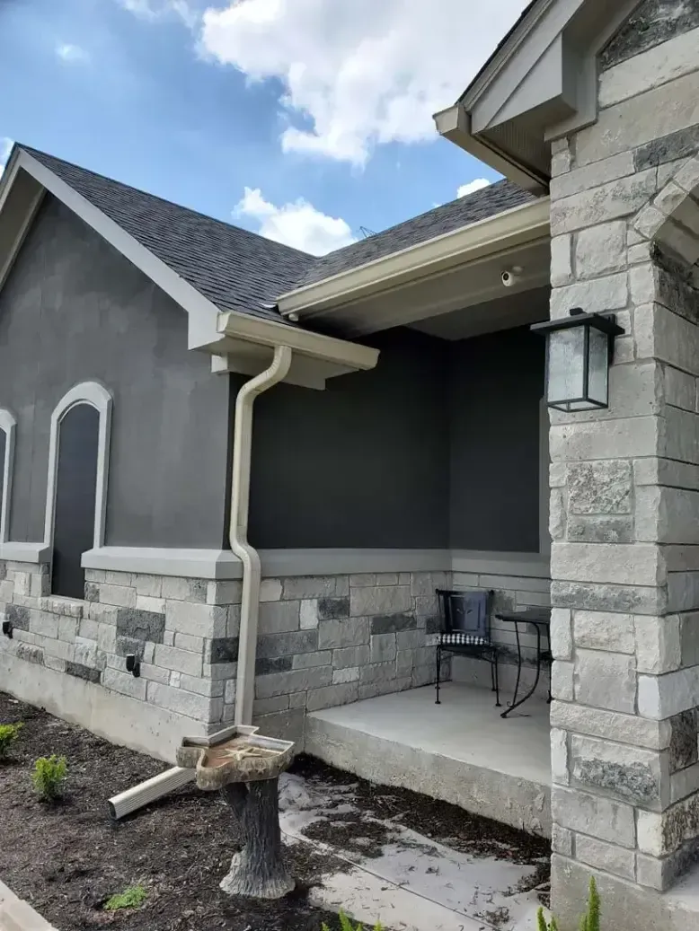 A house with a porch and a gutter on the side of it.