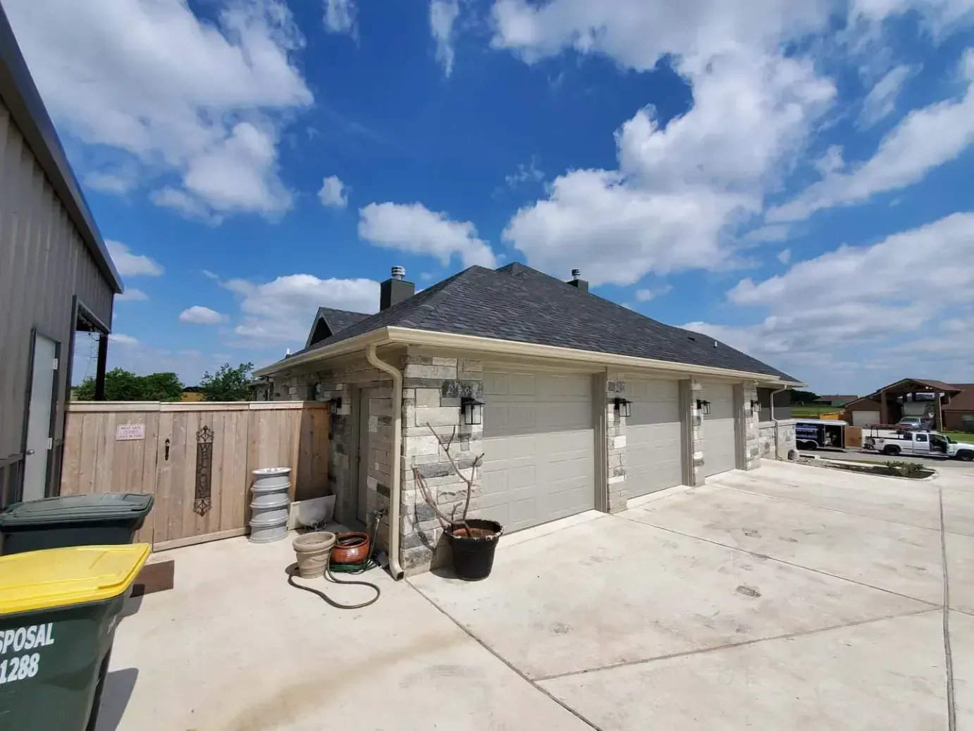 A house with a garage and a trash can in front of it.