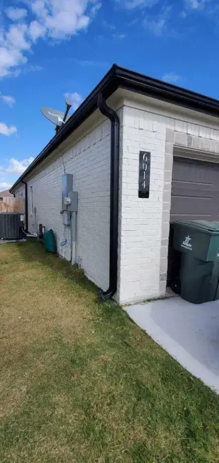 A white house with a black gutter and a garage.
