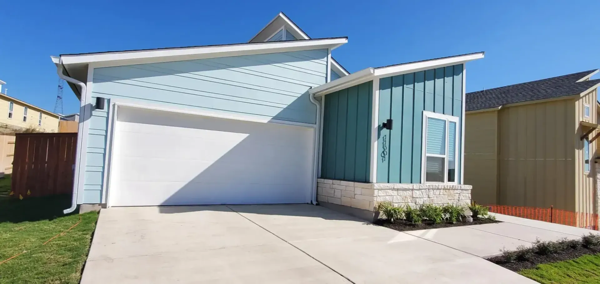 A blue and white house with a white garage door and a driveway.