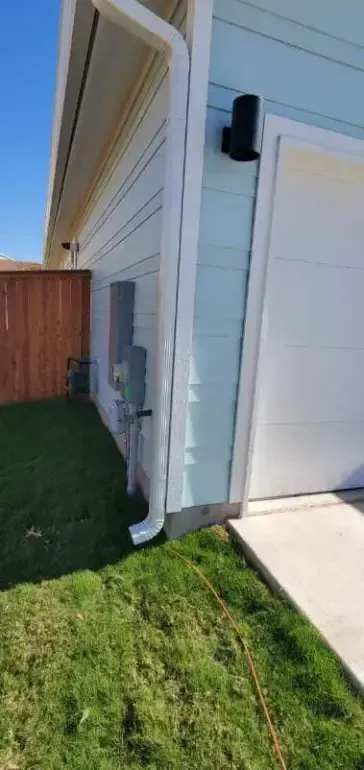 A house with a white garage door and a gutter on the side of it.