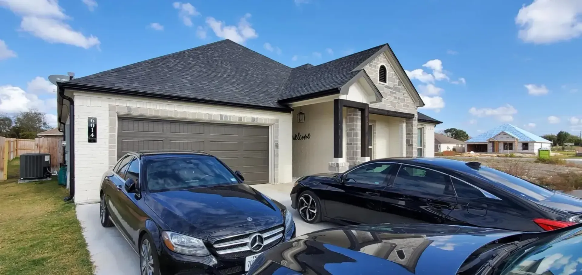 Two cars are parked in front of a house.