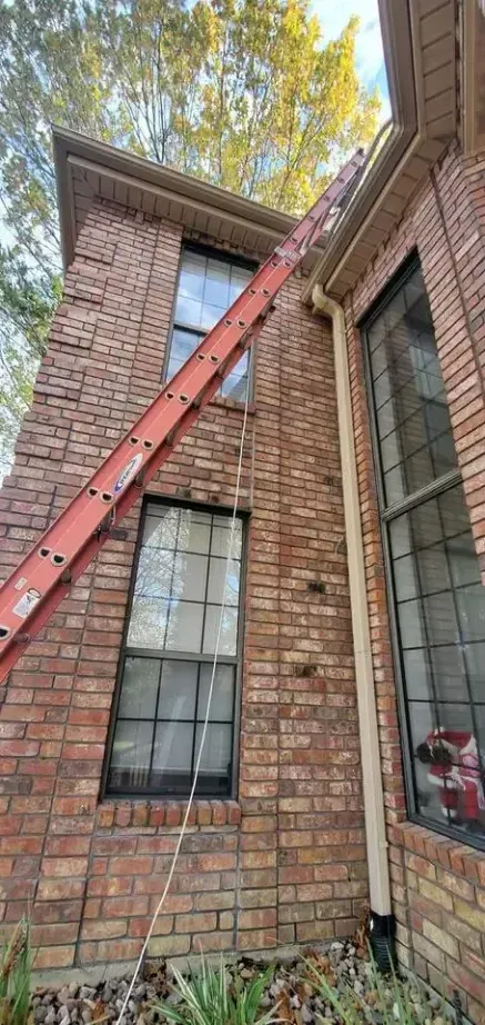 A ladder is hanging from the side of a brick house.