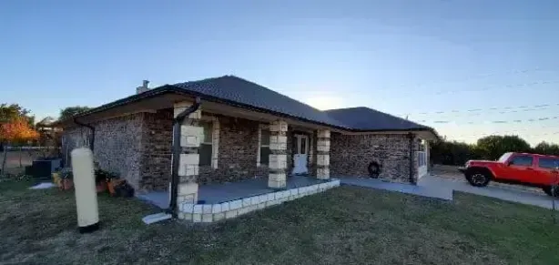 A red truck is parked in front of a stone house.