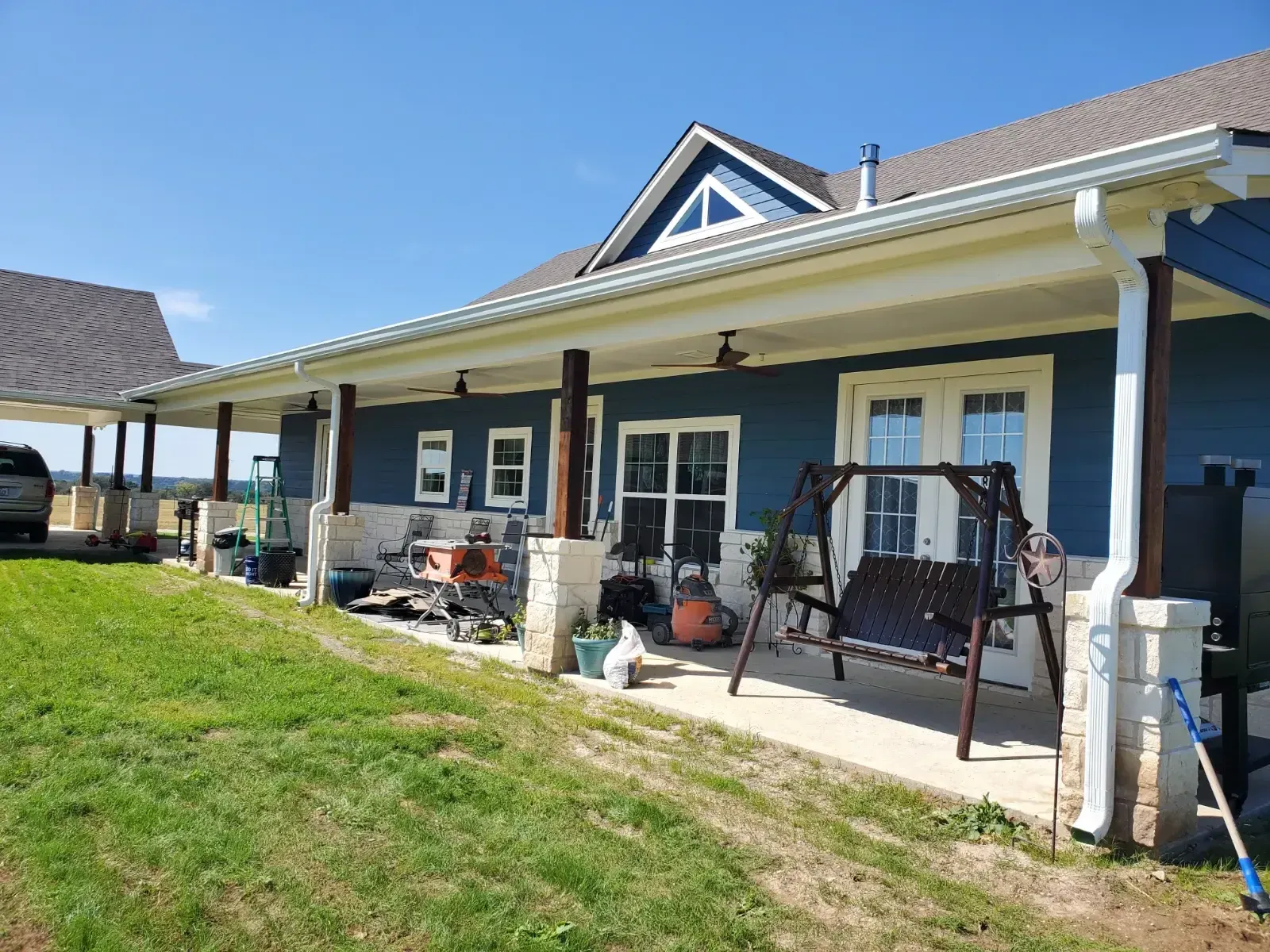 A blue house with a porch and a swing in front of it.
