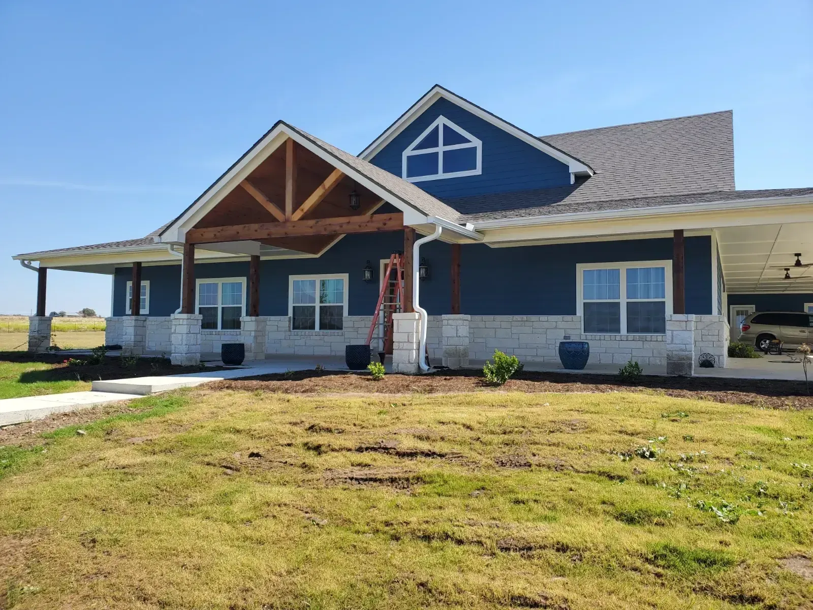 A blue house with a porch and a ladder in front of it