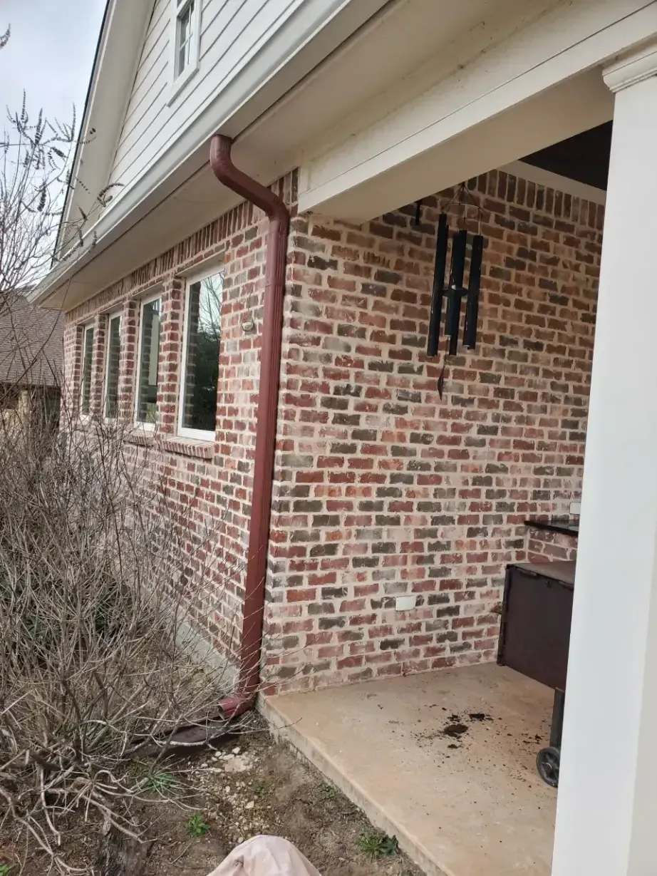 A brick house with a gutter on the side of it.