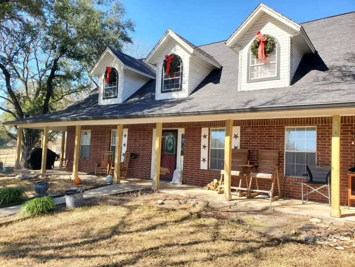 A brick house with a porch and a roof decorated for christmas