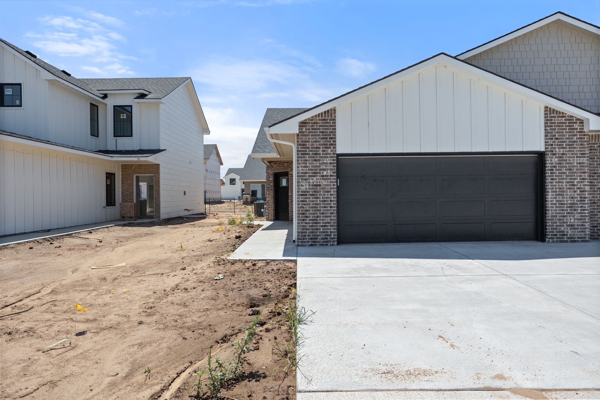 A house with a black garage door is being built in a residential area.