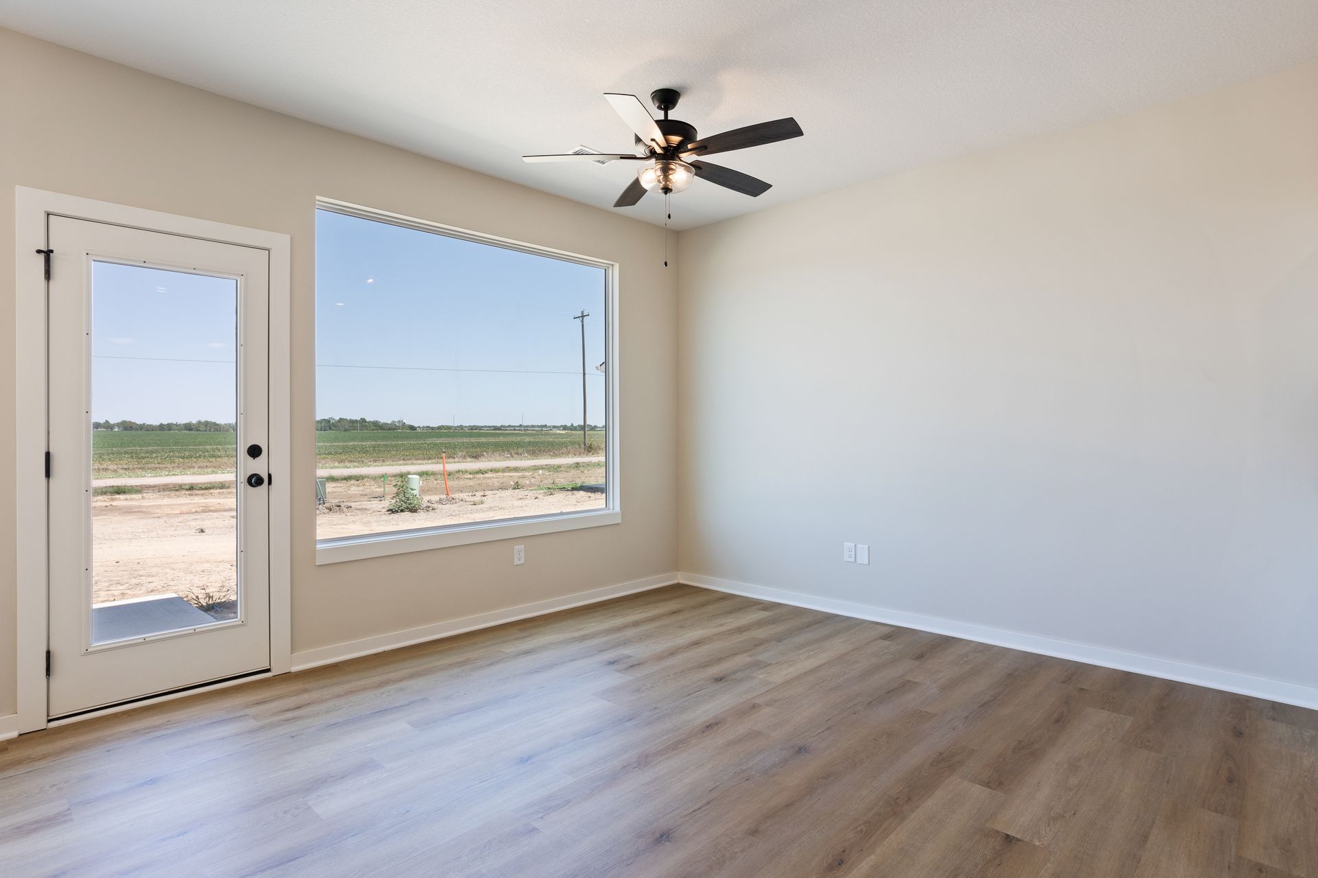 An empty living room with hardwood floors and a ceiling fan.