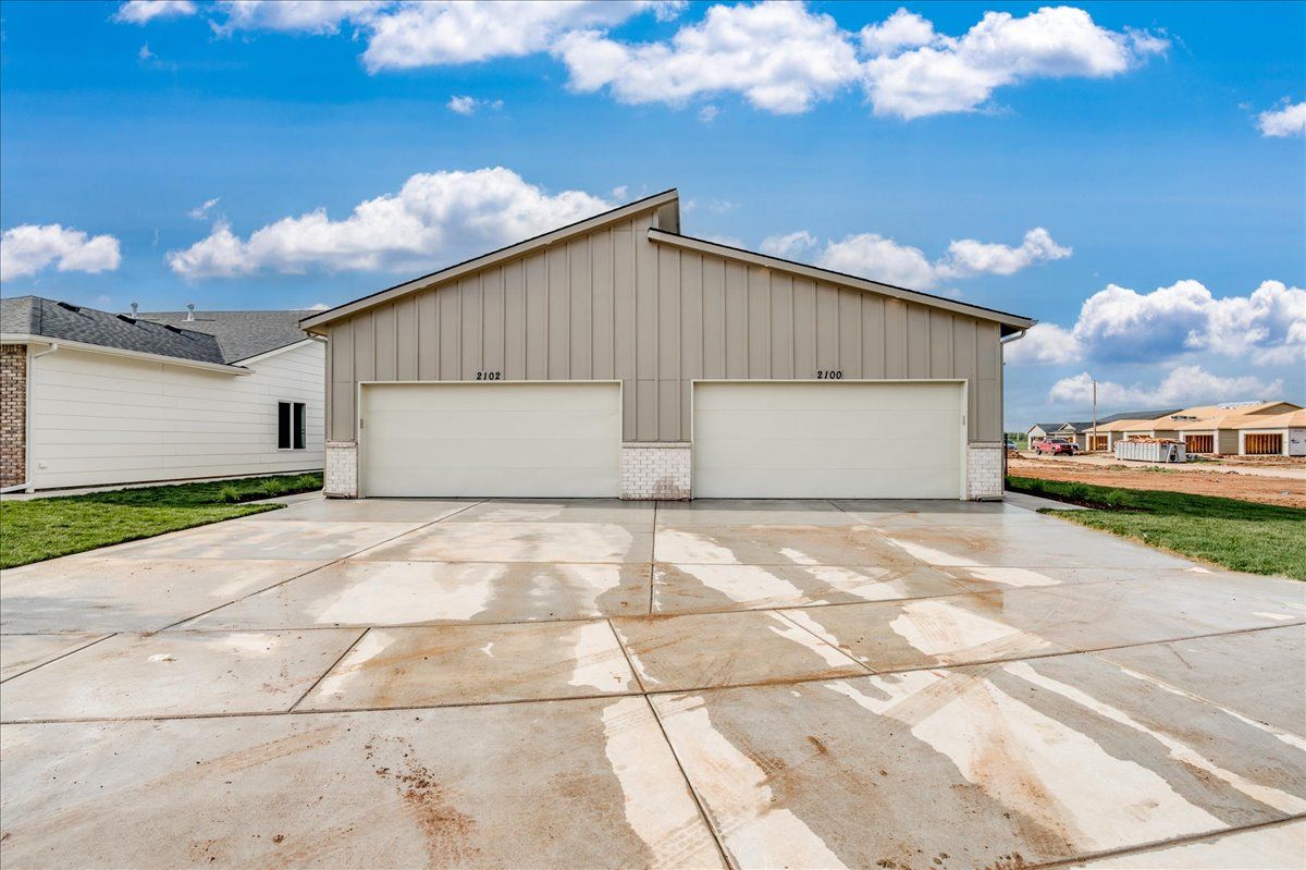 A house with two garage doors and a concrete driveway in front of it.