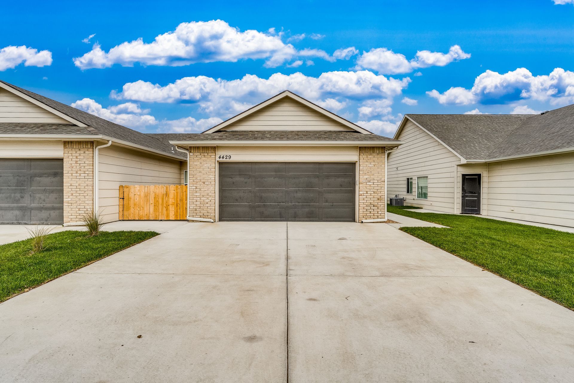 A house with two garages and a fence in front of it.