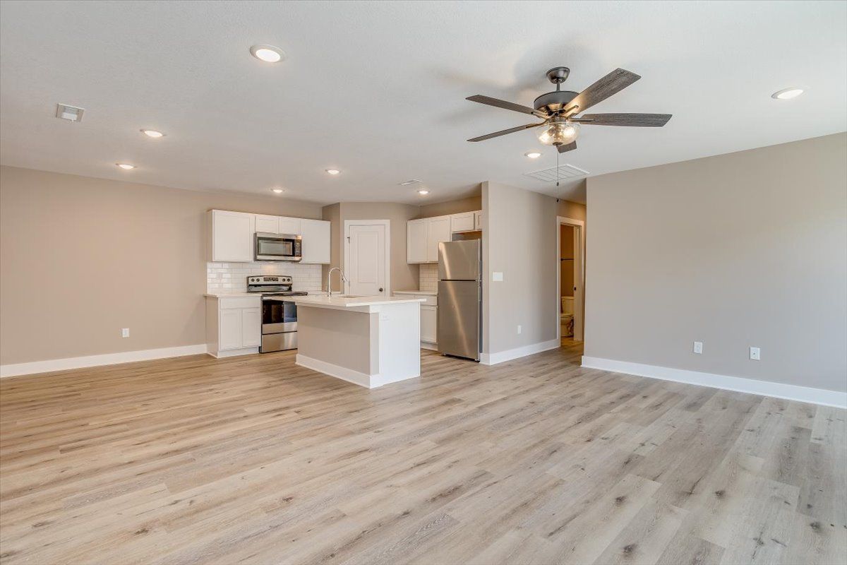 A living room with hardwood floors and a ceiling fan.
