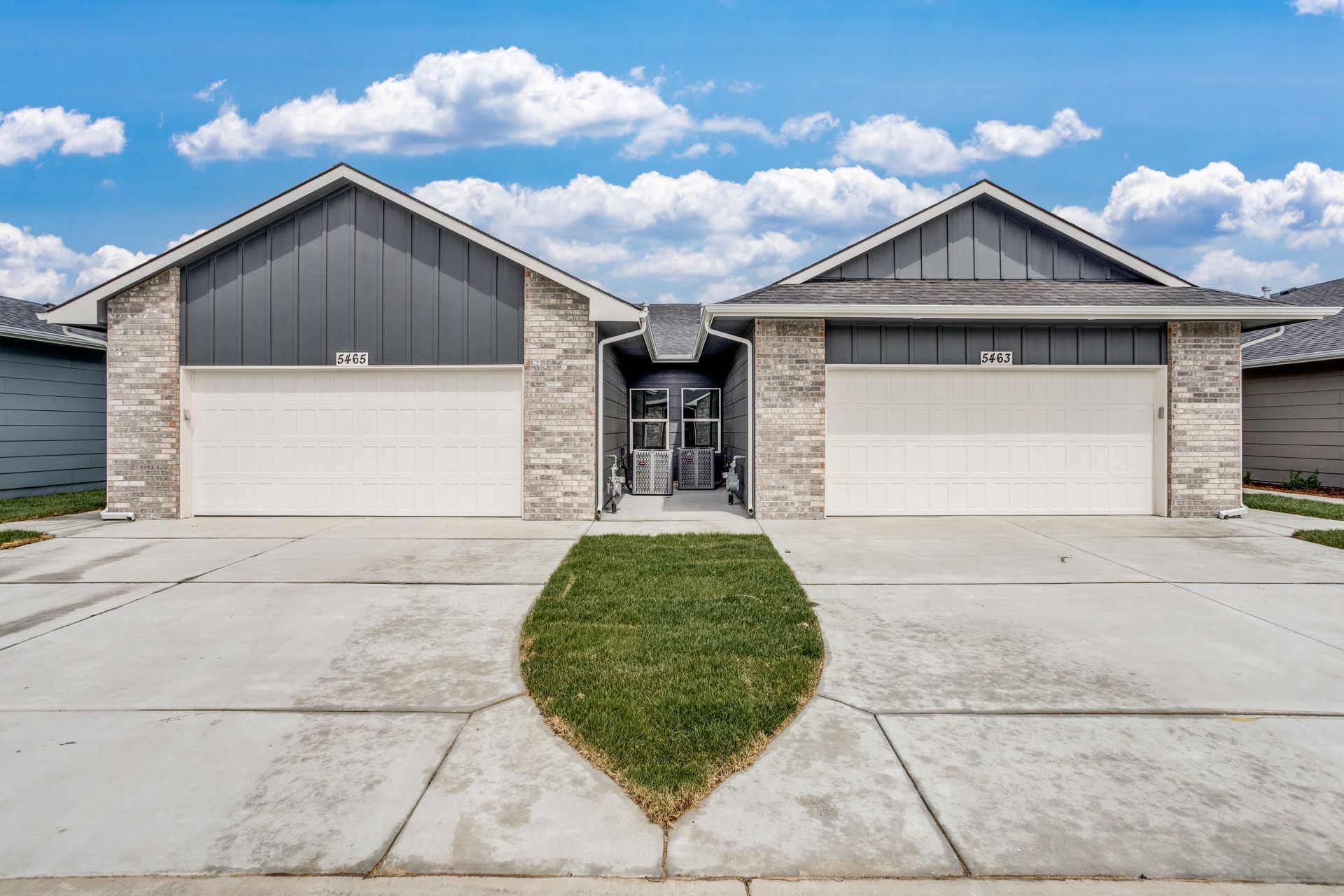 The front of a house with two garage doors and a concrete driveway.