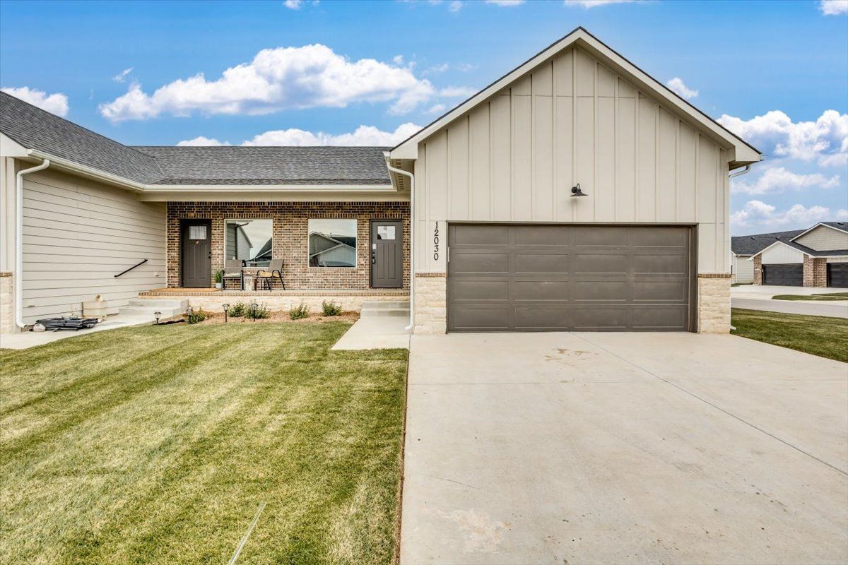 The front of a house with a large garage and a lush green lawn.