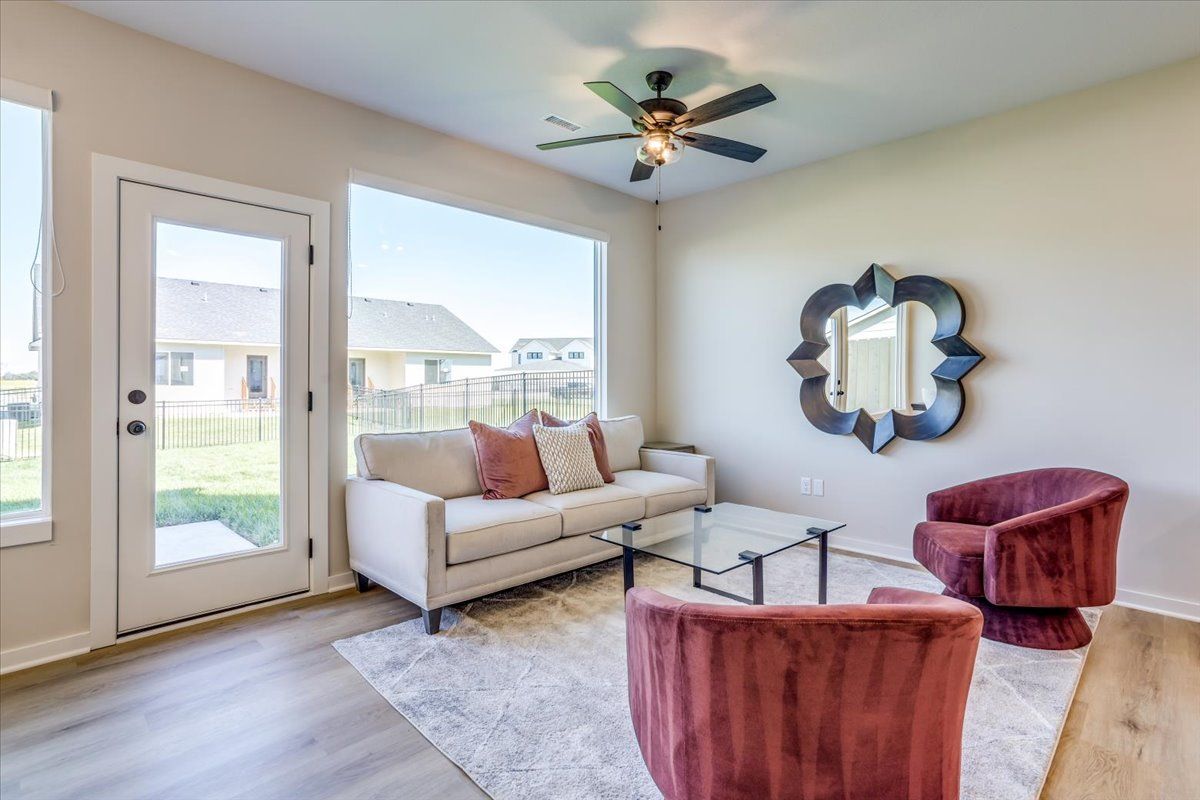 A living room with a couch , chairs , and a ceiling fan.