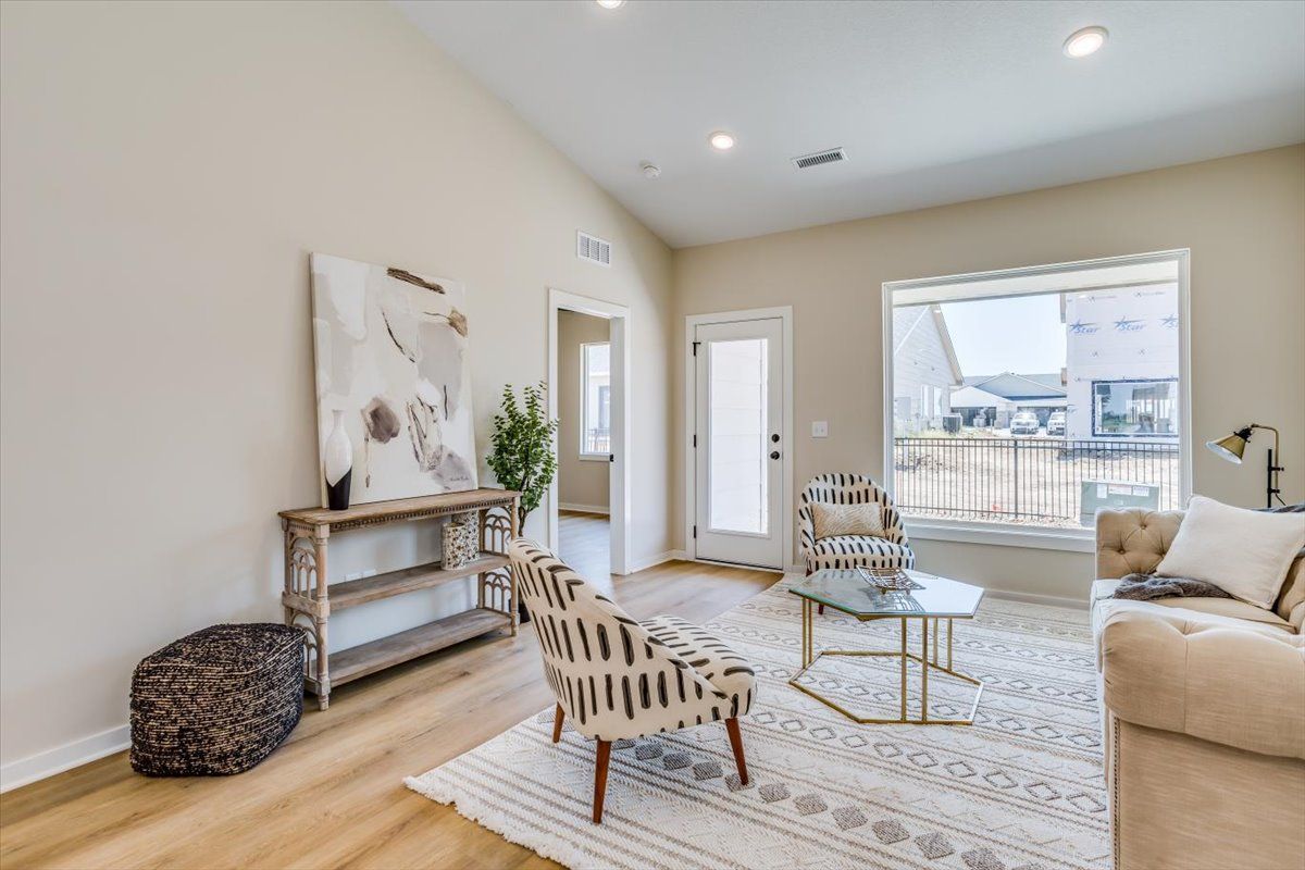 A living room with a couch , chair , coffee table and a painting on the wall.